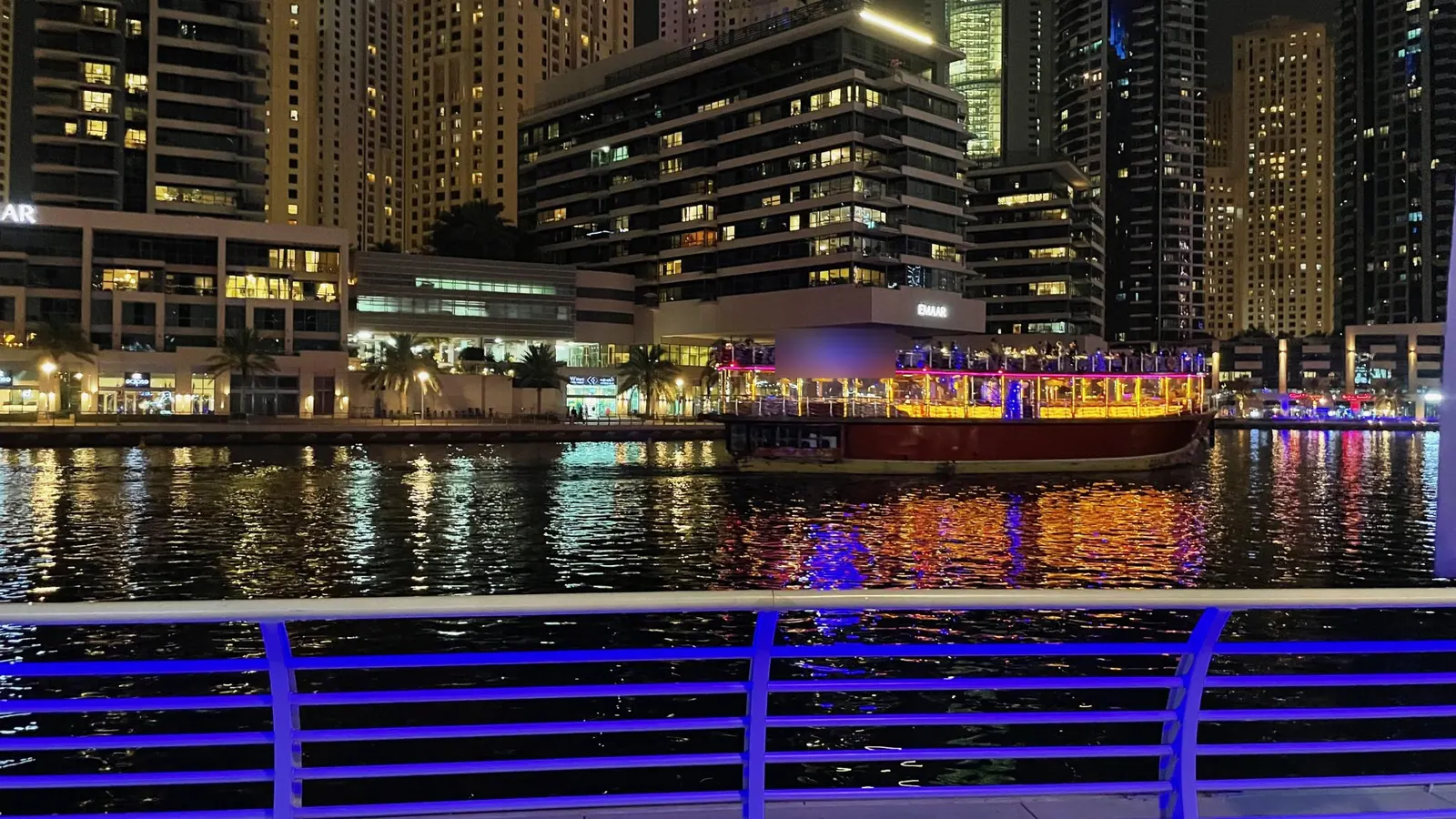 Illuminated wooden dhow cruising Dubai Marina at night